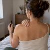 Frau massiert ihre Schulter mit CBD-Öl